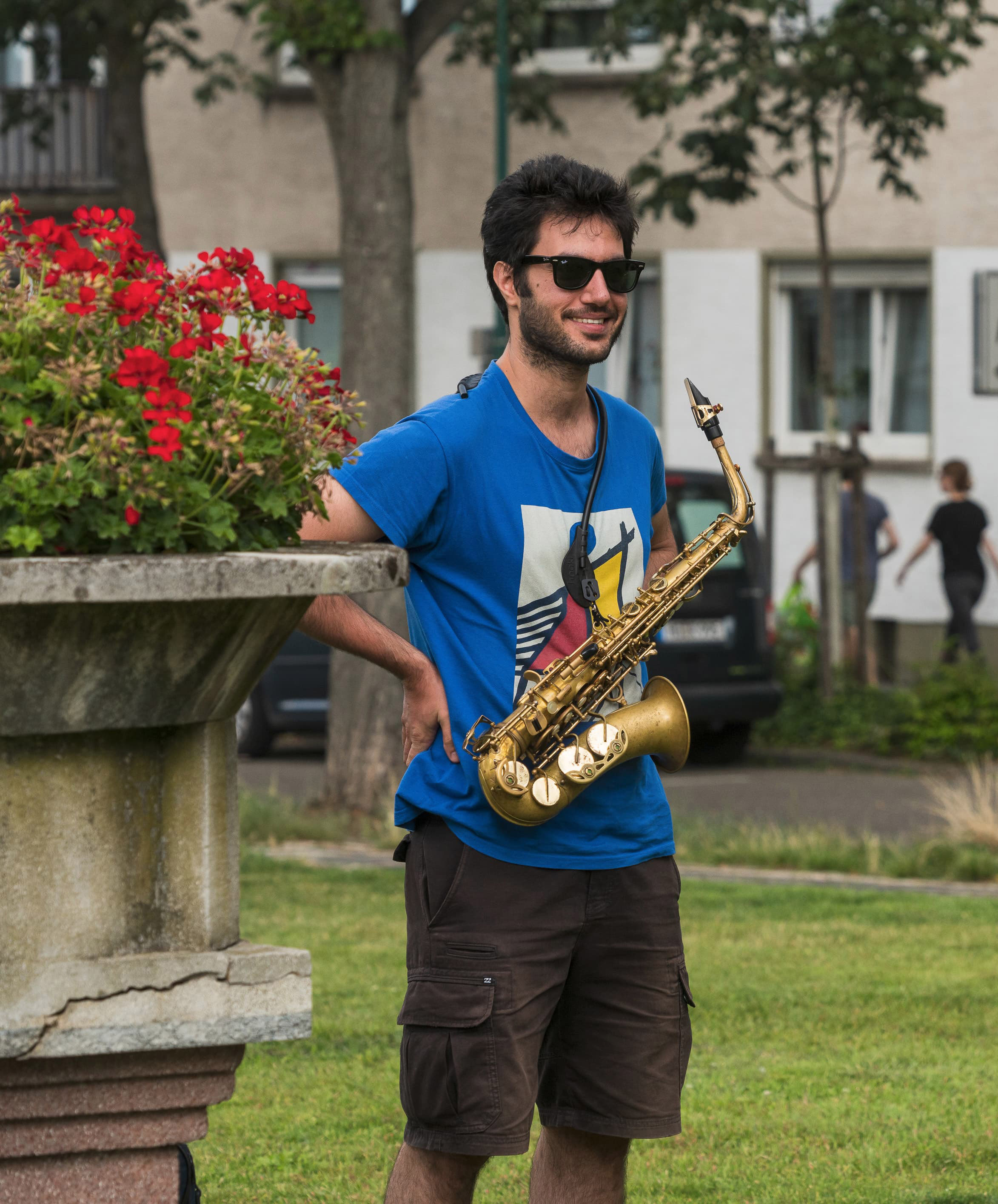 the artist holding the saxophone and wearing sunglasses